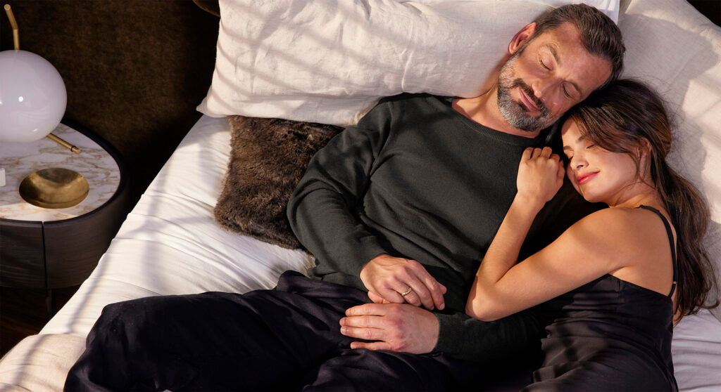 A man and woman sleeping on top of a luxury bed