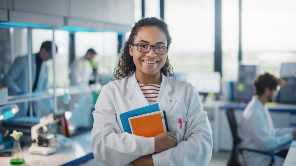 A scientist in a lab holding research notebooks