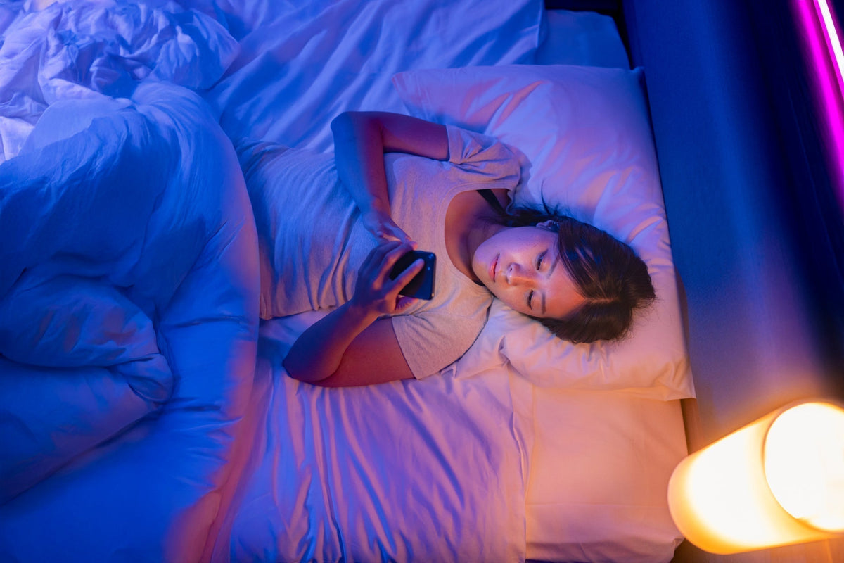 A woman lying in bed looking at her phone