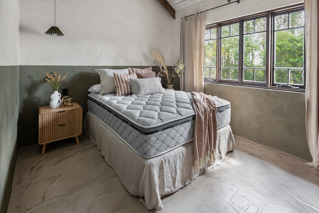 SleepMaker ACA mattress with blankets and pillows in a bedroom setting
