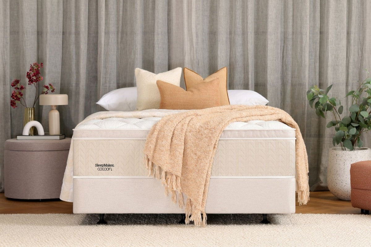 SleepMaker Cocoon mattress with blankets and pillows in a bedroom setting