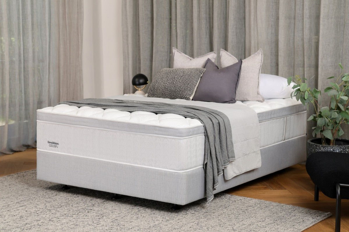 SleepMaker Cocoon mattress with blankets and pillows in a bedroom setting