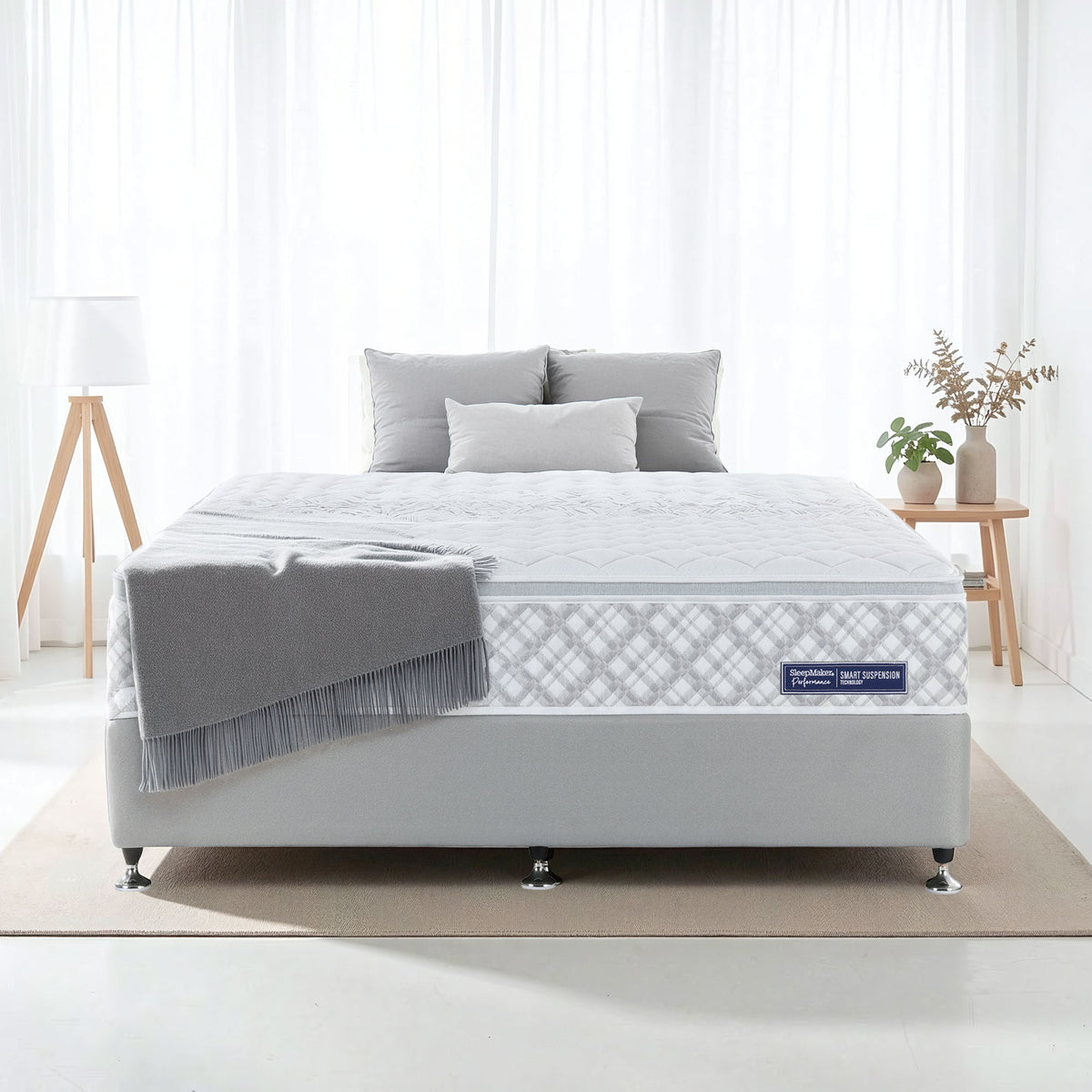SleepMaker Performance mattress with blankets and pillows in a bedroom setting