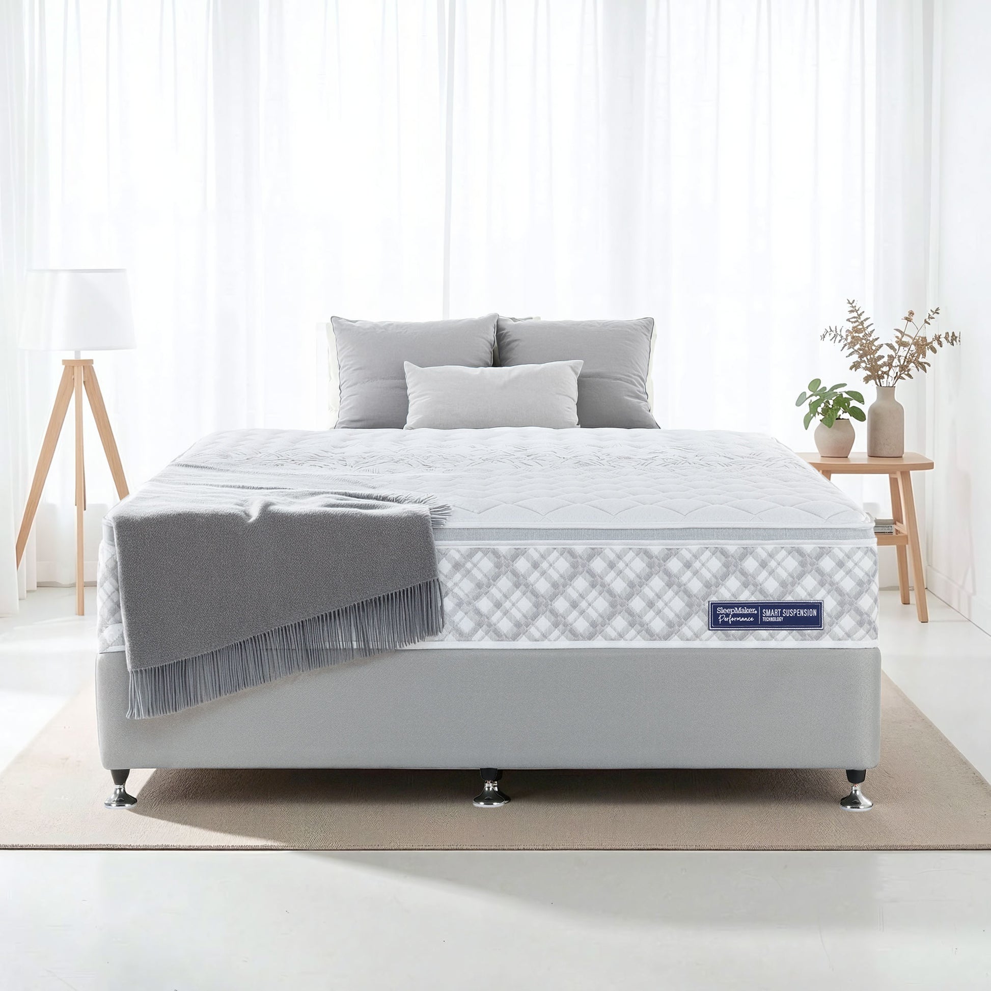 SleepMaker Performance mattress with blankets and pillows in a bedroom setting