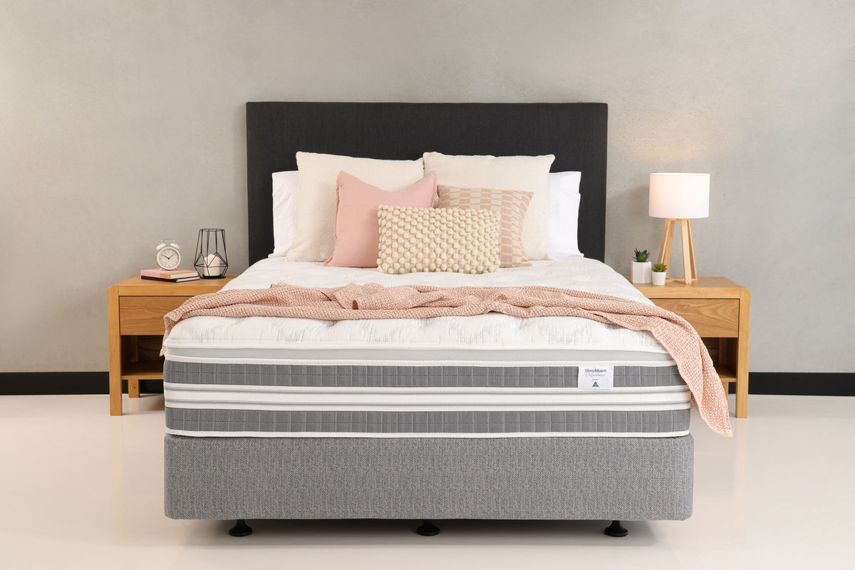 SleepMaker Performance mattress with blankets and pillows in a bedroom setting