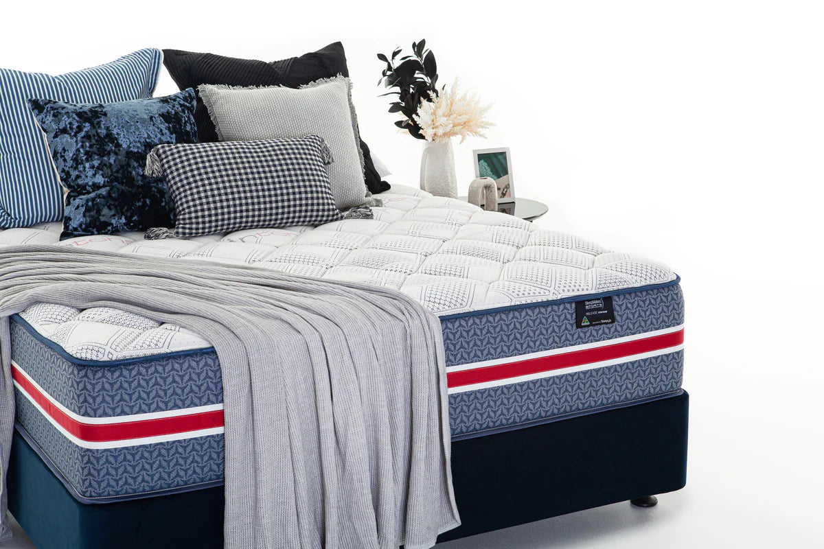 SleepMaker Sports Performance mattress with blankets and pillows in a bedroom setting