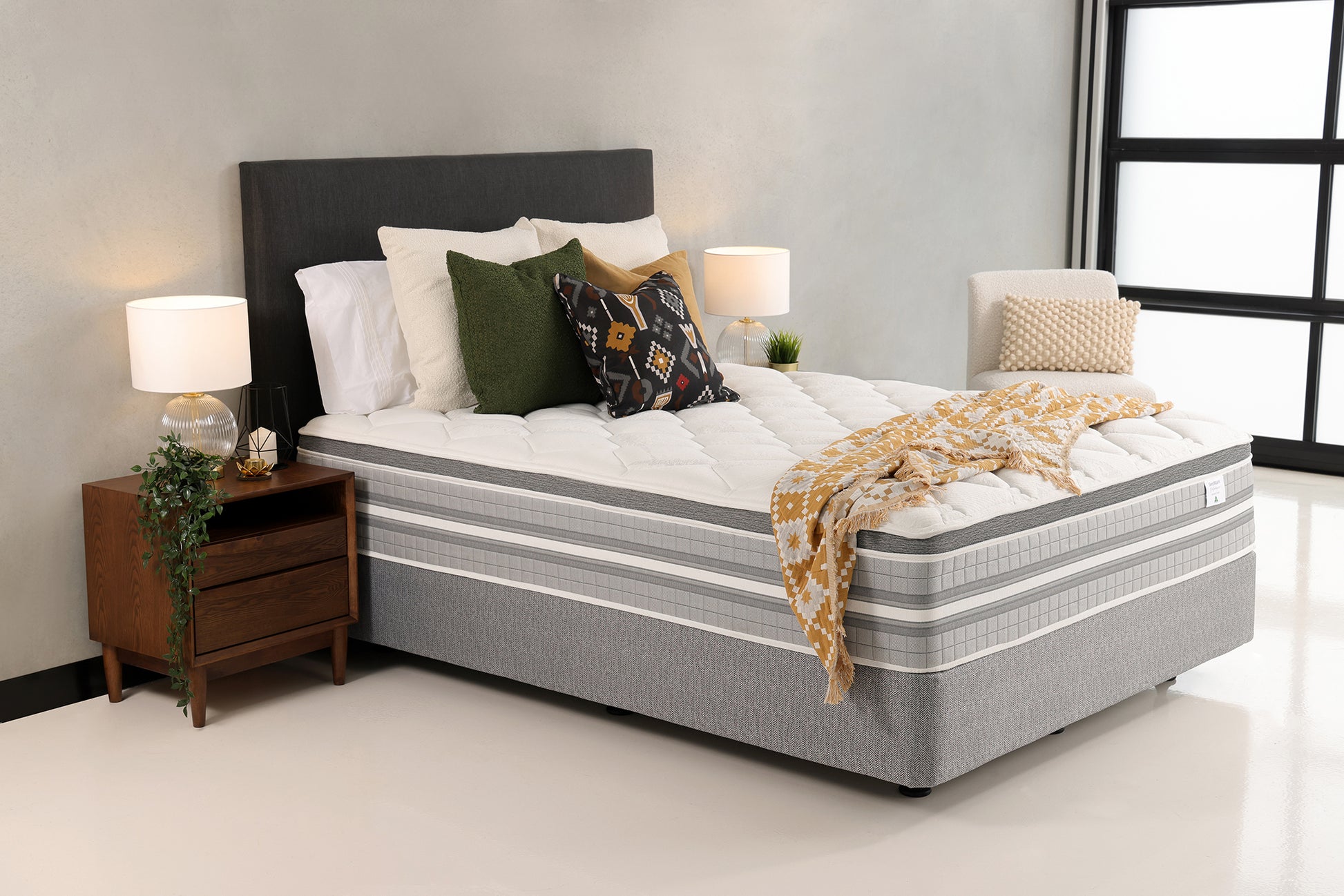 SleepMaker Lifestyle mattress with blankets and pillows in a bedroom setting