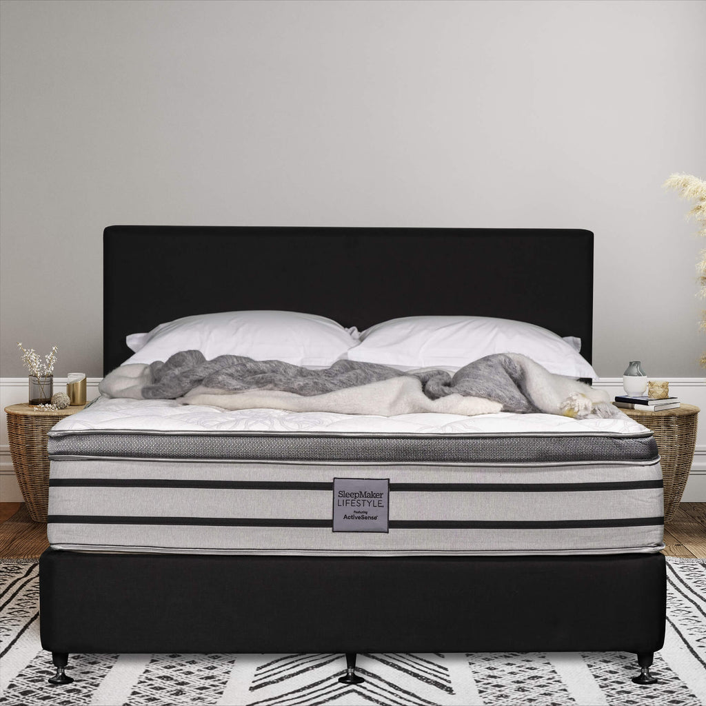 SleepMaker Lifestyle mattress with blankets and pillows in a bedroom setting