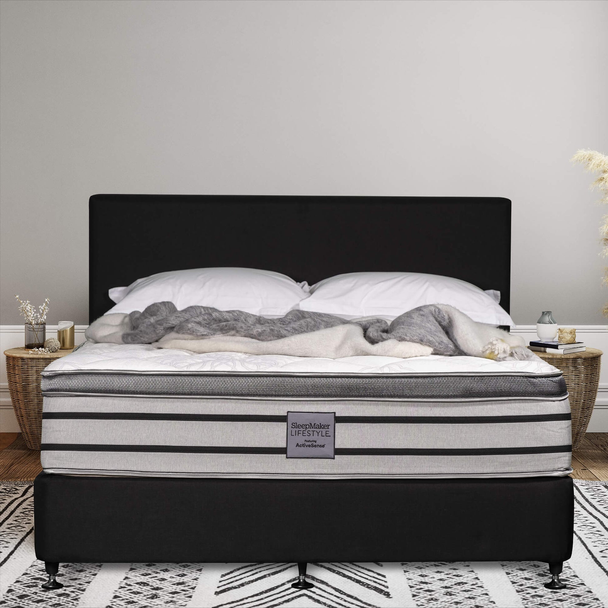 SleepMaker Lifestyle mattress with blankets and pillows in a bedroom setting