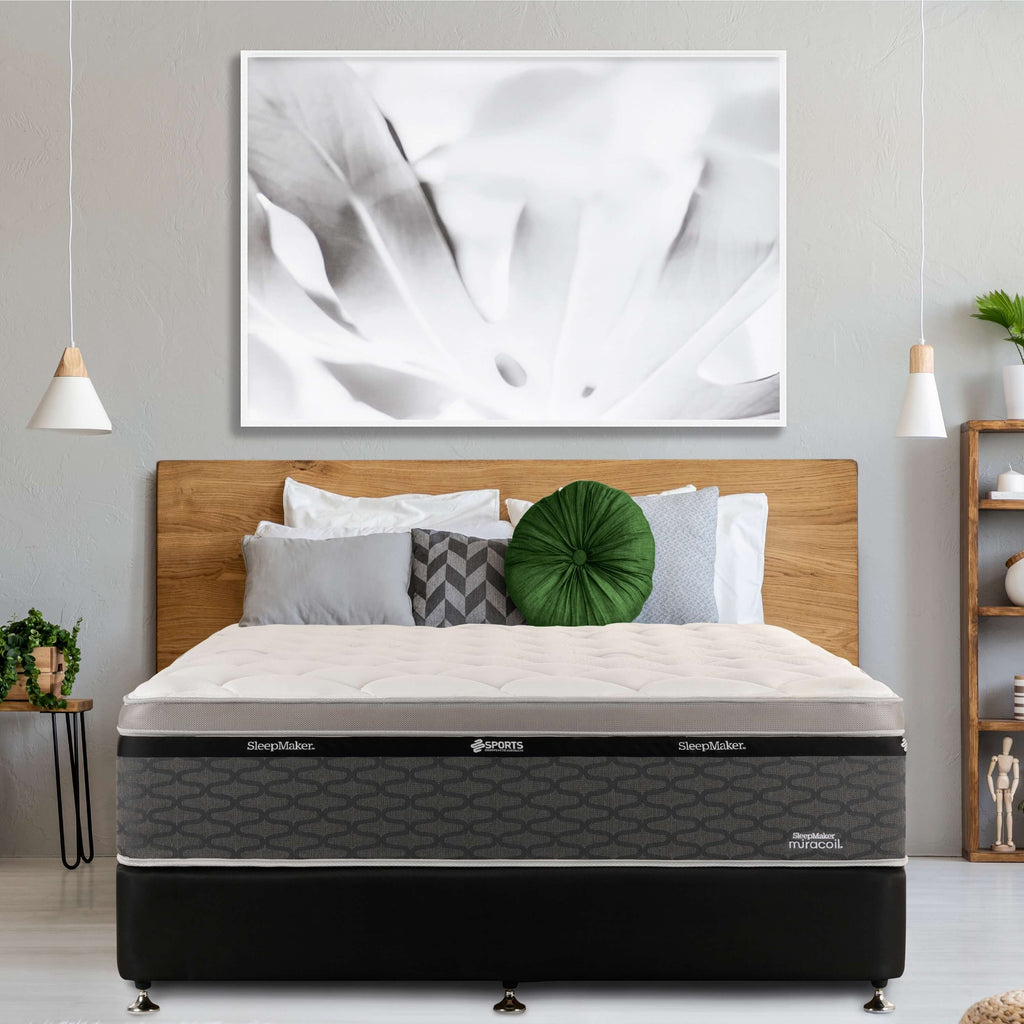 SleepMaker Miracoil mattress with blankets and pillows in a bedroom setting