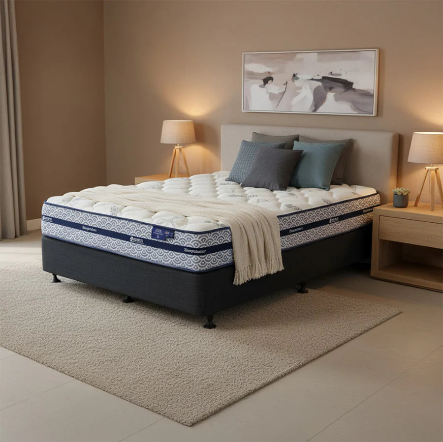 SleepMaker Miracoil mattress with blankets and pillows in a bedroom setting