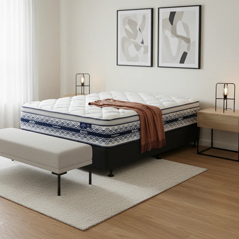 SleepMaker Miracoil mattress with blankets and pillows in a bedroom setting