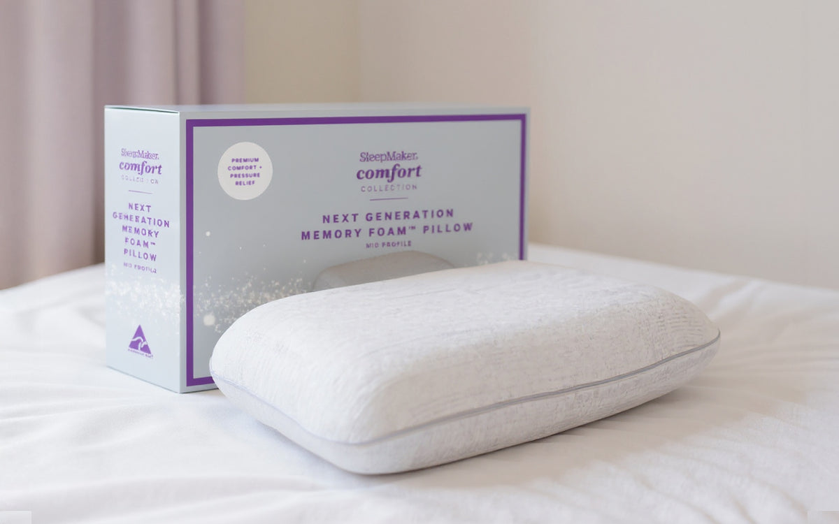 SleepMaker Comfort Collection pillow on a bed with packaging in the background