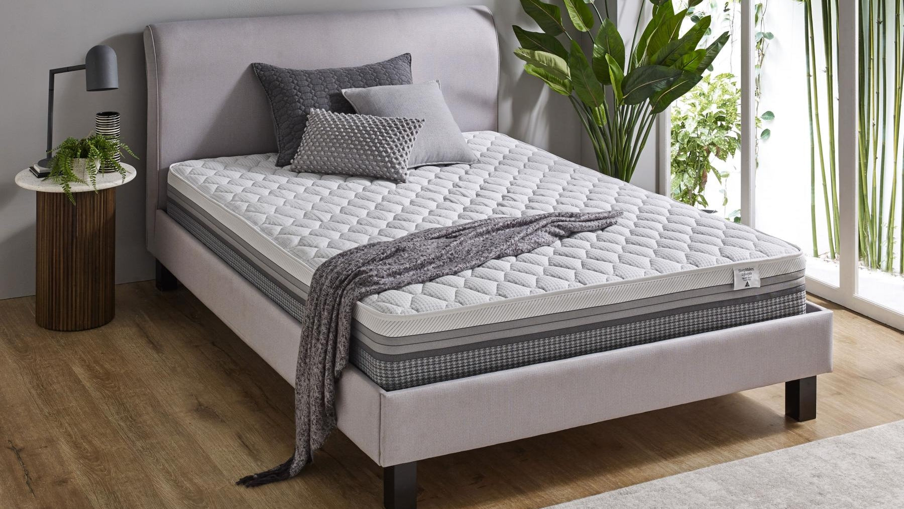 SleepMaker Lifestyle mattress with blankets and pillows in a bedroom setting