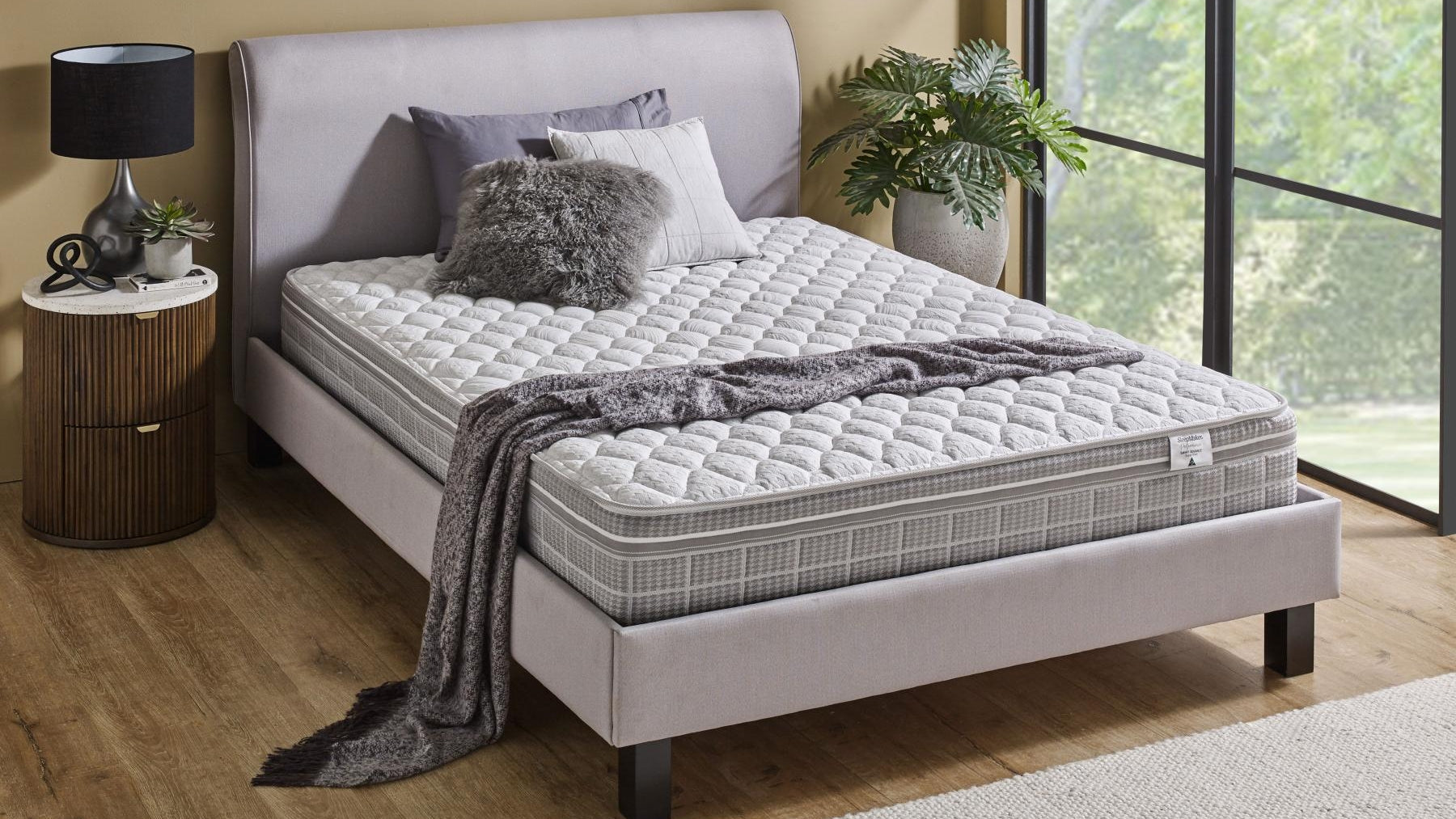 SleepMaker Performance mattress with blankets and pillows in a bedroom setting