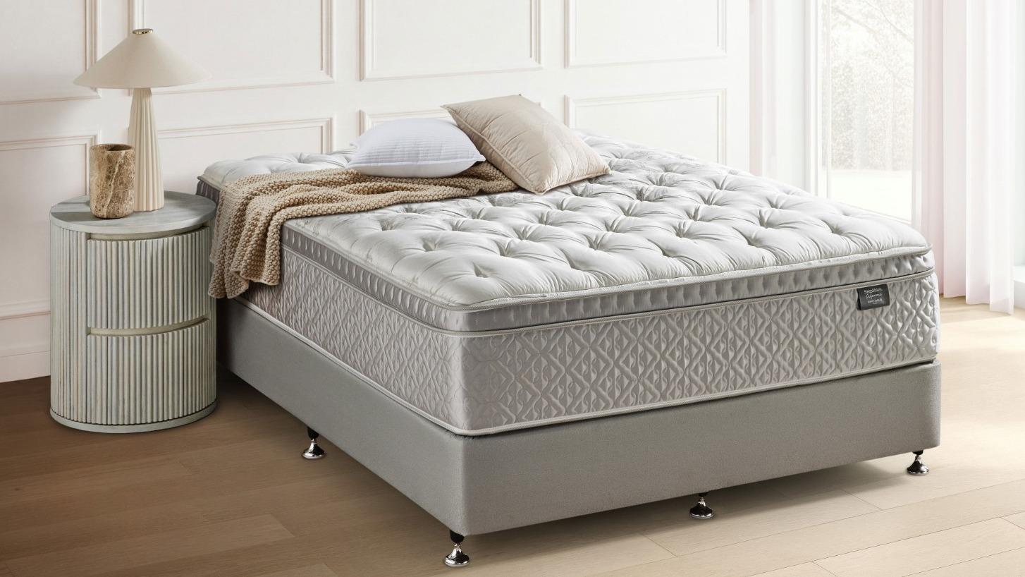 SleepMaker Performance mattress with blankets and pillows in a bedroom setting