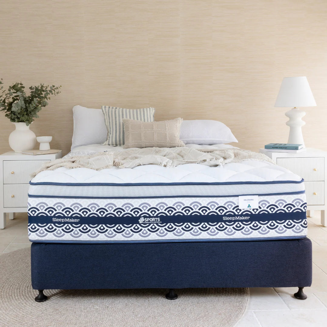 SleepMaker Miracoil mattress with blankets and pillows in a bedroom setting
