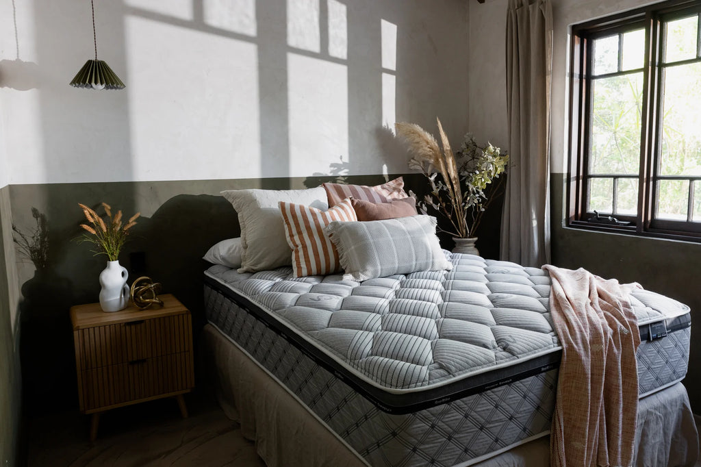 SleepMaker Miracoil mattress with blankets and pillows in a bedroom setting