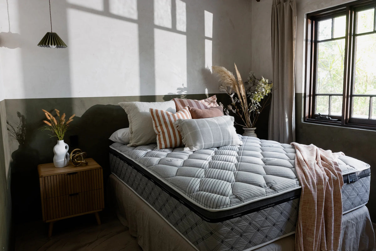 SleepMaker Miracoil mattress with blankets and pillows in a bedroom setting