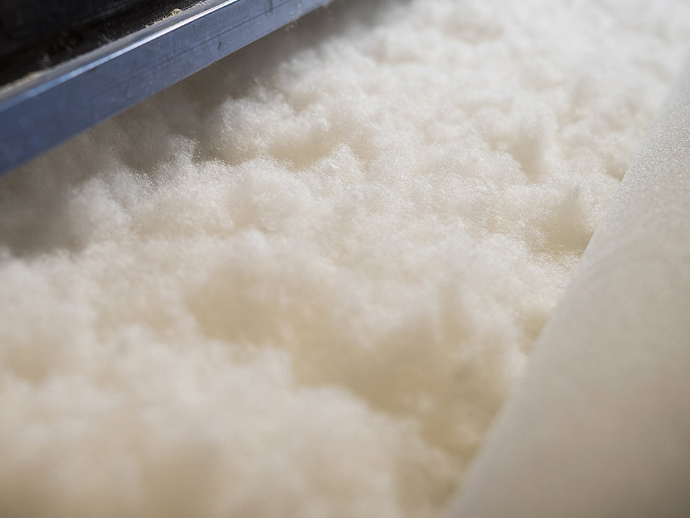 Close-up of white cotton fibers with a blue tool on a white background