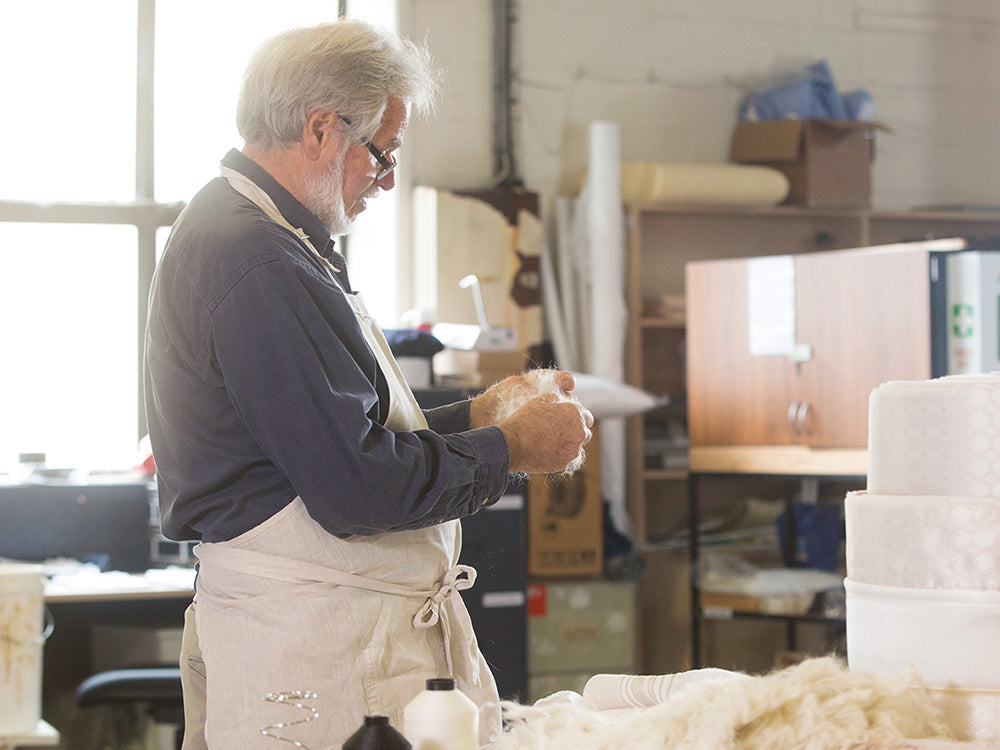 Man working with mattress materials in a workshop setting