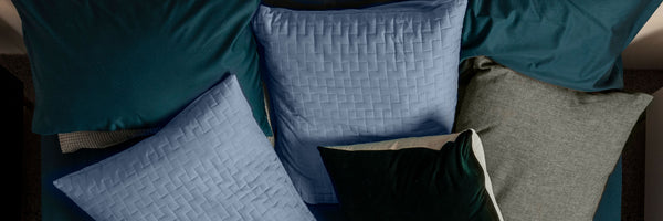 Collection of various textured SleepMaker pillows in different colors on a sofa.