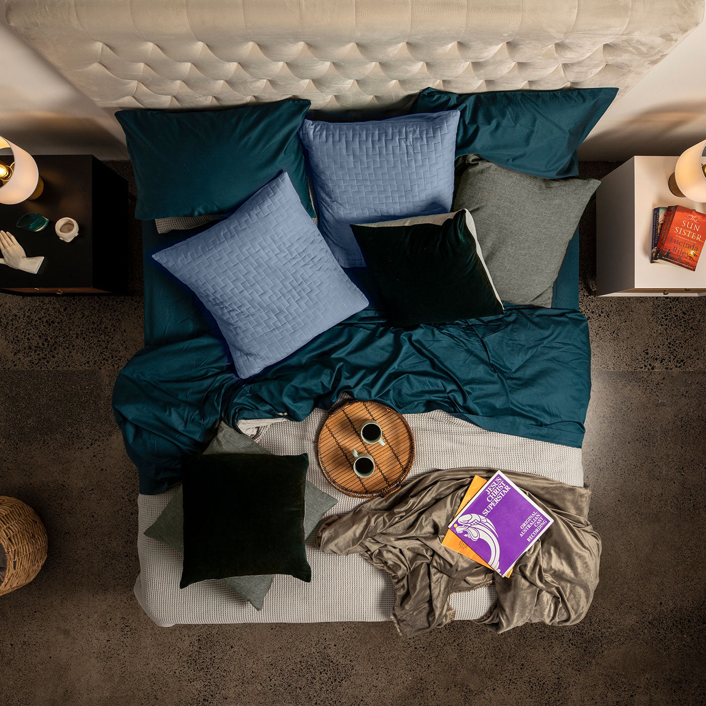 Top-down view of a SleepMaker bed with colorful pillows and a blanket, with a nightstand and books on either side.
