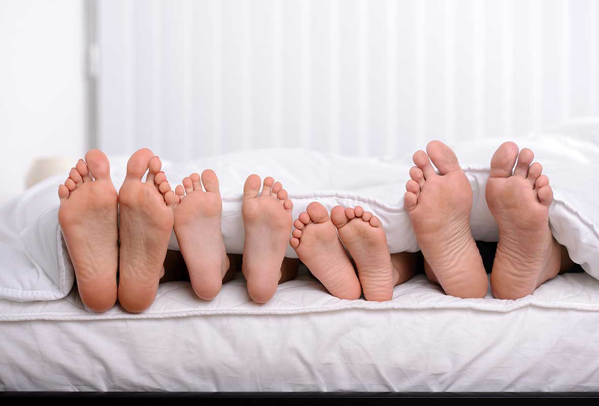 a family lying on a bed showing their feet